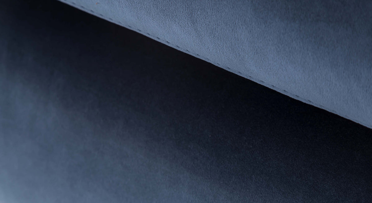 Gros plan sur le tissu velours bleu nuit du canapé convertible Miles, revêtement douce et élégante