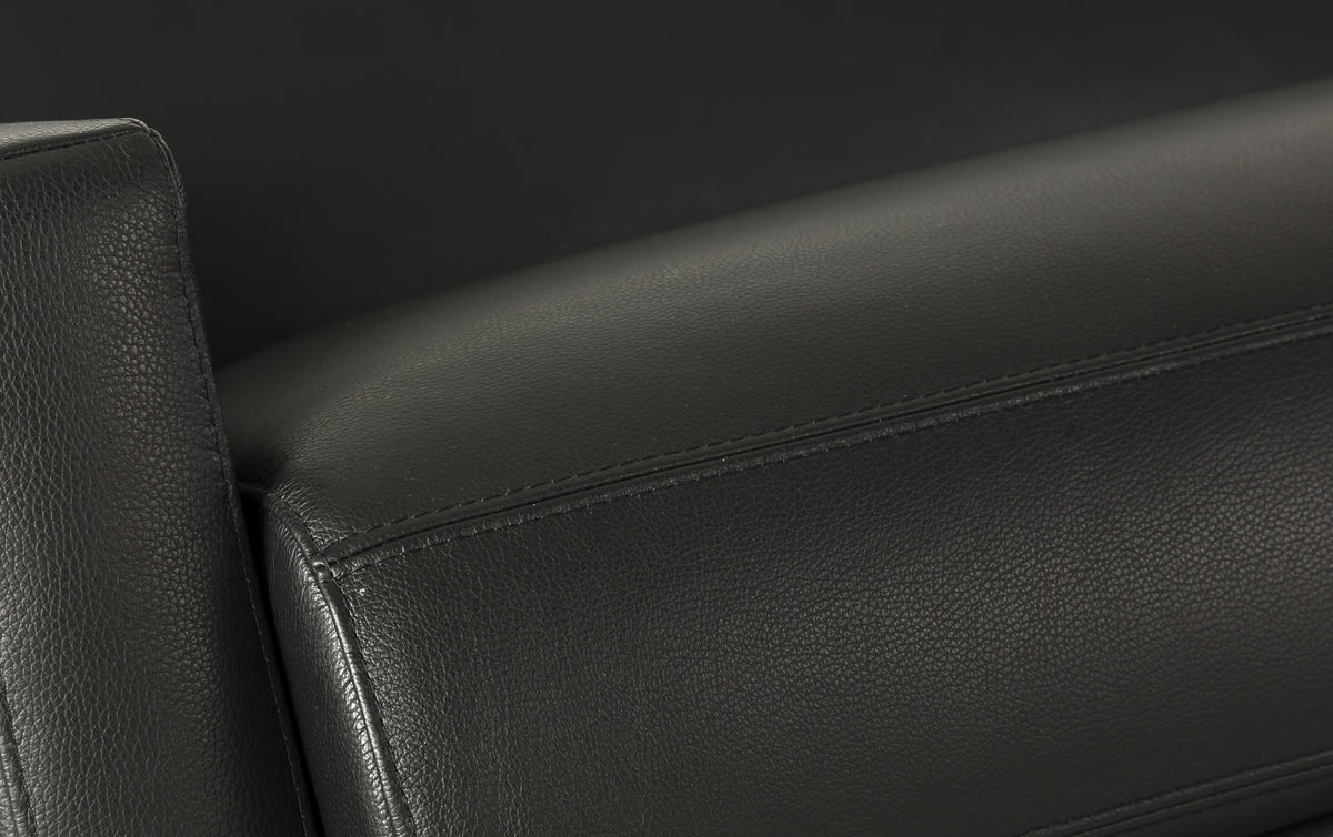 Zoom sur le cuir noir d'un canapé convertible de luxe, montrant la revêtement et les coutures détaillées