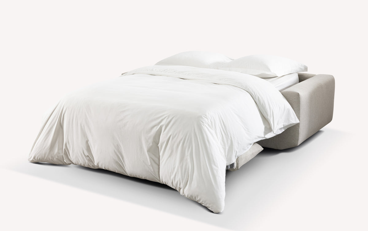Lot canapé droit et pouf STELLA déployé en canapé convertible avec couchage confortable, recouvert d’une housse en tissu beige clair, idéal pour un usage quotidien.