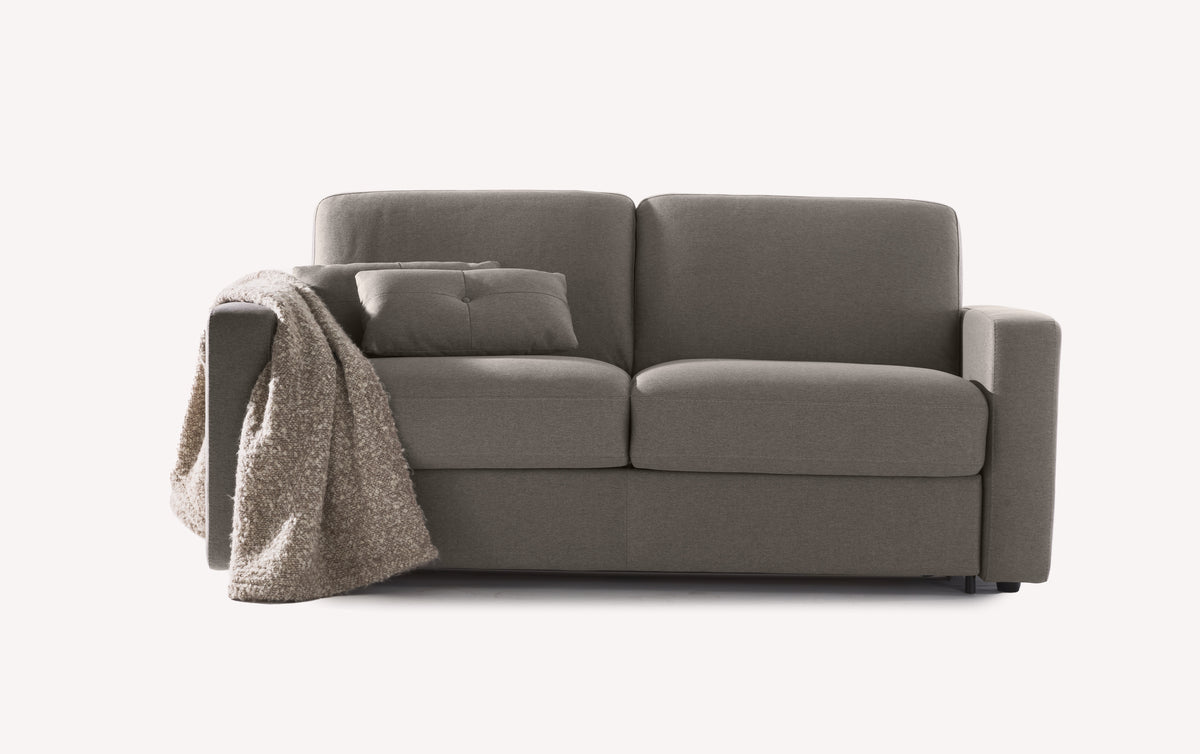 Canapé convertible en tissu gris Luna Brume, modèle Will, avec coussin et plaid texturé sur l'accoudoir