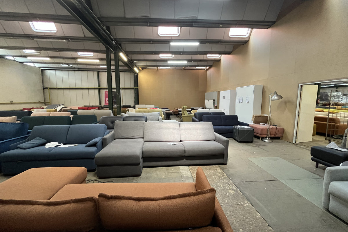 Salle d'exposition à Gonesse avec divers canapés colorés alignés sous un éclairage industriel