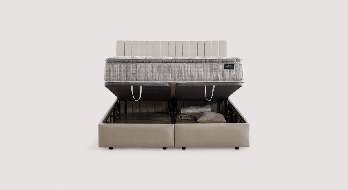 Lit coffre Amsterdam avec matelas relevé, montrant un espace de rangement contenant des couvertures et un oreiller