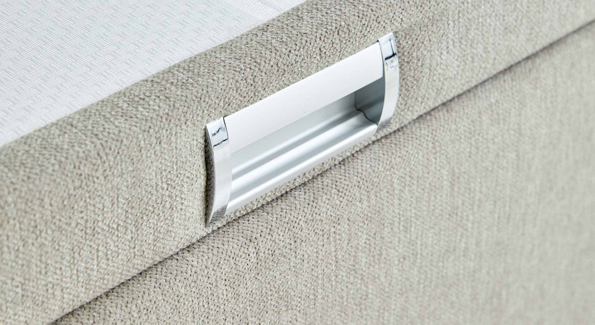 Détail d’une poignée en métal moderne sur un tissu beige clair, partie du Lit coffre WARREN BOX Guard Liver, offrant un espace de rangement pratique et élégant.