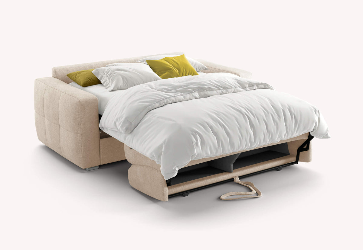 Canapé convertible beige SONY Aragon Ivoire déplié en lit avec couette blanche et coussins verts, idéal pour couchage quotidien avec vrai matelas confortable.